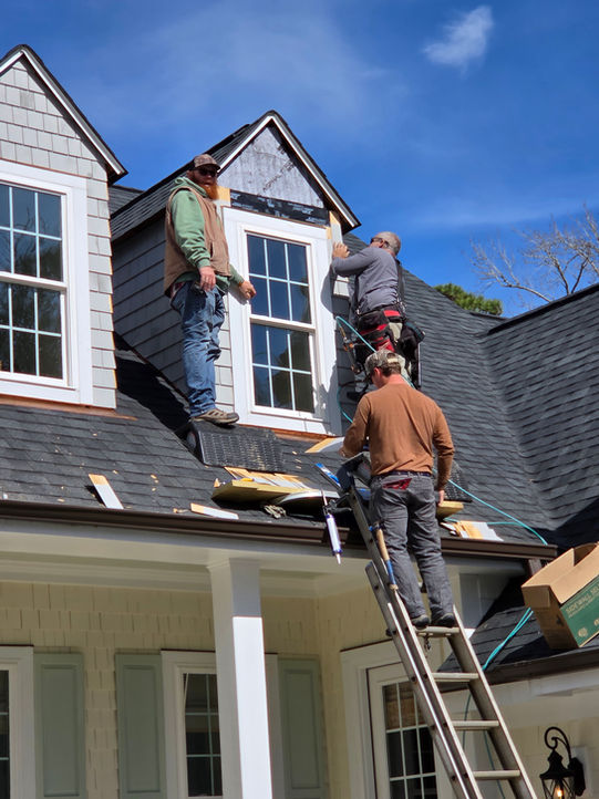 Contractors installing dormer windows on a residential roof.