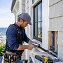 Technician applying sealant to a window frame for water intrusion repair.