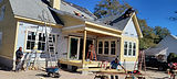 Contractors installing exterior trim and siding on a house.