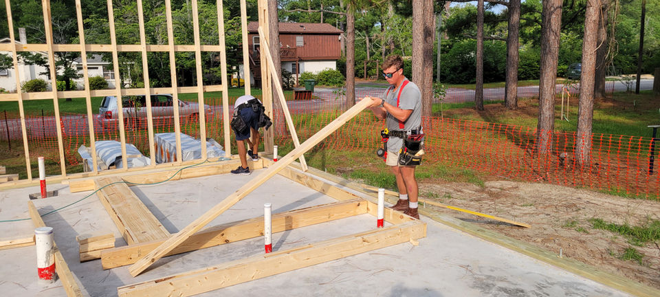 Carpenters framing a new house on a concrete foundation