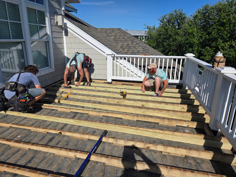 Contractors installing wooden joists for a deck construction.