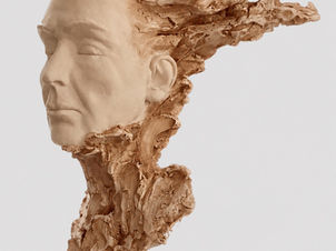 Side-profile view of Fire & Ice, a clay portrait sculpture featuring a serene, refined face surrounded by expressive, flame-like textures, photographed against a light-gray background.