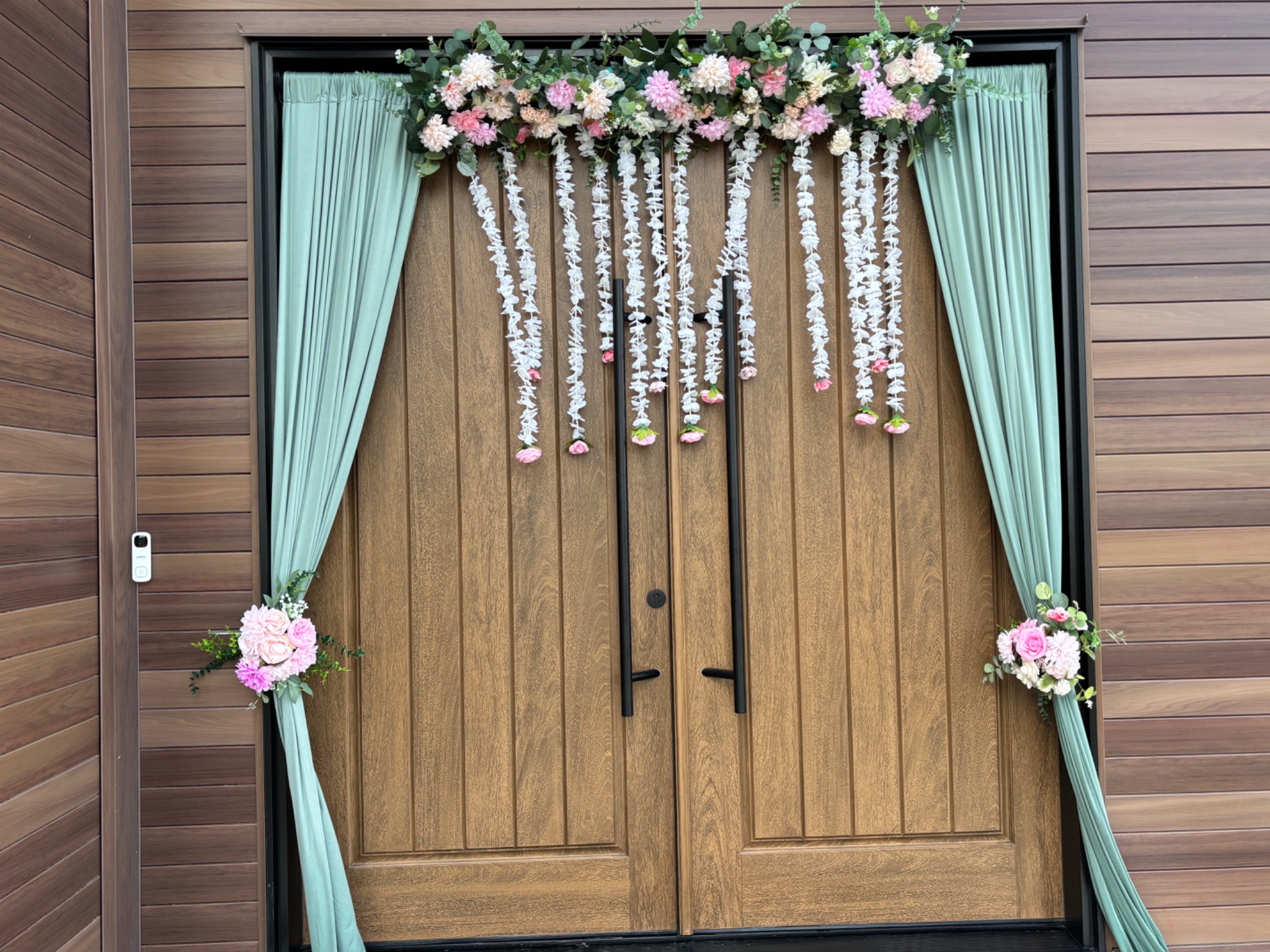 Sage draped doorway with hanging florals for a South Asian celebration