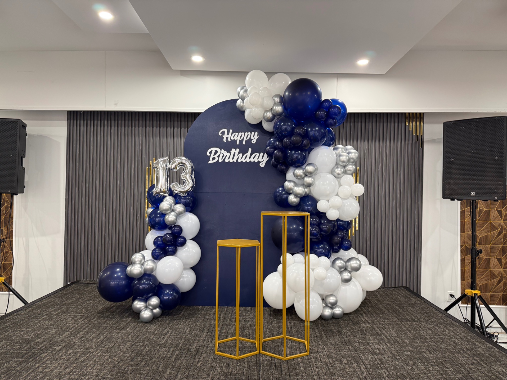 Navy, white and silver birthday backdrop with champagne-gold plinths