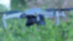 Gray drone hovering outdoors with "Mavic Air 2" text on the side, against a blurred green and purple background.