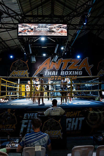 A fight night at Antza Muay Thai in Hua Hin is a lively evening of genuine competitive Muay Thai, usually featuring around 6–7 bouts between Thai and international fighters. The action takes place close to the crowd, so expect traditional Muay Thai rituals, live fight music, hard kicks, knees, elbows and the possibility of dramatic knockouts. You can also see Antza's confirmed dates on our Hua Hin Muay Thai Stadiums page.
⠀
Antza isn't a staged Muay Thai demonstration for tourists. These are real fights, and that unpredictability is a big part of the experience.
⠀
What Happens at Antza Muay Thai in Hua Hin?
⠀
The evening features a series of Muay Thai bouts rather than one single fight.
⠀
Before fighting begins, you'll see elements of traditional Muay Thai culture, including fighters performing the Wai Kru and Ram Muay before competing.
⠀
Then the atmosphere changes as the fights get underway.
⠀
Fighters can use punches, kicks, knees, elbows and clinch techniques under full Muay Thai rules.
⠀
Some bouts develop into tactical contests that continue through the scheduled rounds. Others can finish suddenly with a knockout or referee stoppage.
⠀
That's live Muay Thai. Nobody knows exactly what's going to happen next.
⠀
What Is the Atmosphere Like at Antza?
⠀
Antza puts spectators close to the ring, which makes the fights feel considerably more intense than watching them on a screen.
⠀
You'll hear the traditional music accompanying the action, the fighters' corners calling instructions and the crowd responding when somebody lands a clean technique.
⠀
You also hear something television doesn't quite capture properly.
⠀
The impact.
⠀
When a kick lands cleanly and you're sitting only a few metres away, there's no need for anybody to explain how powerful Muay Thai is.
⠀
How Close Can I Sit to the Ring?
⠀
Antza offers Standard and VIP seating, with the VIP section particularly limited.
⠀
There are currently only around 10 VIP seats, putting a small number of spectators particularly close to the action.
⠀
If sitting near the ring is important to you, booking the VIP option beforehand makes sense rather than relying on those limited seats still being available on fight night.
⠀
Current VIP tickets also include one complimentary drink.
⠀
Standard seating still gives you the complete stadium atmosphere and a good view of the fights.
⠀
What Time Does an Antza Fight Night Start?
⠀
Antza fights currently begin at 9:00 PM, with the doors opening at approximately 8:00 PM.
⠀
You don't need to arrive the moment the doors open.
⠀
Getting there at around 8:15–8:30 PM gives you time to enter, find your seat and settle in before the first fight begins.
⠀
Antza is located on Soi Bonkai 24, just off Soi 94, and can be reached by taxi, Grab or local transport.
⠀
How Long Does an Antza Fight Night Last?
⠀
Allow around 2–3 hours for the complete fight night.
⠀
There isn't an exact finishing time because the length of the evening depends on what happens in the individual bouts.
⠀
Several early stoppages can shorten the night, while fights going the distance can make it run longer.
⠀
If you're arranging transport afterwards, it's better to keep your finishing time flexible.
⠀
Is Antza Good for First-Time Muay Thai Spectators?
⠀
Yes.
⠀
You don't need to understand Muay Thai scoring or recognise any of the fighters before you arrive.
⠀
Watch the opening fights and you'll soon begin noticing how fighters use distance, kicks, knees and the clinch.
⠀
By the later bouts, most first-time spectators are following considerably more of the action than they expected.
⠀
Antza also welcomes families. Children under 8 currently receive free admission, although parents should remember that this is genuine full-contact combat sport and children may see knockouts or cuts.
⠀
What Makes Watching Muay Thai at Antza Different?
⠀
It's the combination of sport and atmosphere.
⠀
You aren't simply watching two people fight. You're seeing the fighters prepare, the traditional rituals before the bouts, the corners working between rounds and the rhythm of a real Thai fight night developing around you.
⠀
Sitting close enough to see the fighters' reactions and hear the impact makes the experience particularly memorable.
⠀
And because every bout is genuine competition, the evening never follows a script.
⠀
What Should I Expect From My First Antza Fight Night?
⠀
Come expecting a relaxed stadium atmosphere before the fights and considerably more noise once the action starts.
⠀
Arrive a little early, find your seat and don't worry if you know absolutely nothing about the fighters on the card.
⠀
A night at Antza Muay Thai in Hua Hin is about experiencing genuine Muay Thai at close range: the traditions, music, crowd, fighters and the sudden moments of action that can change a bout in seconds.
⠀
You might arrive simply wanting to see Muay Thai while you're in Thailand.
⠀
By the end of the night, you'll probably have picked a favourite fighter.