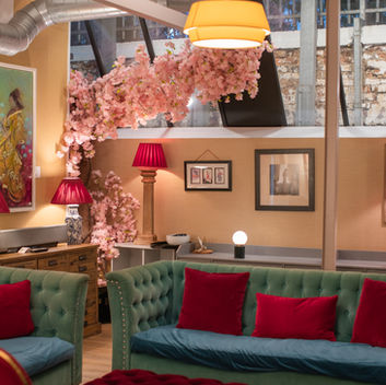 Stylish lounge with green velvet sofas, red cushions, pink cherry blossoms, and lamps in a warm, cozy interior. LGBTQ+ Friendly wedding venue in London