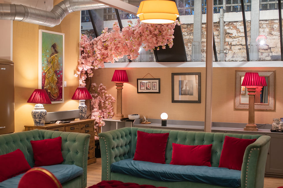 Stylish lounge with green velvet sofas, red cushions, pink cherry blossoms, and lamps in a warm, cozy interior. LGBTQ+ Friendly wedding venue in London