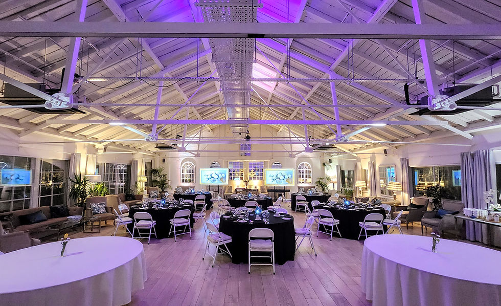 Elegant banquet hall with round tables, white chairs, purple lighting, and large screens on the far wall, set for an event. LGBTQ+ Friendly wedding venue in London