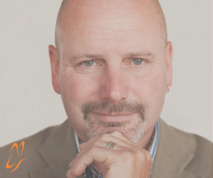 Image shows Martin Crump a man in his 50's with a grey goatee. Martin is wearing a suit with blue and white stripey shirt