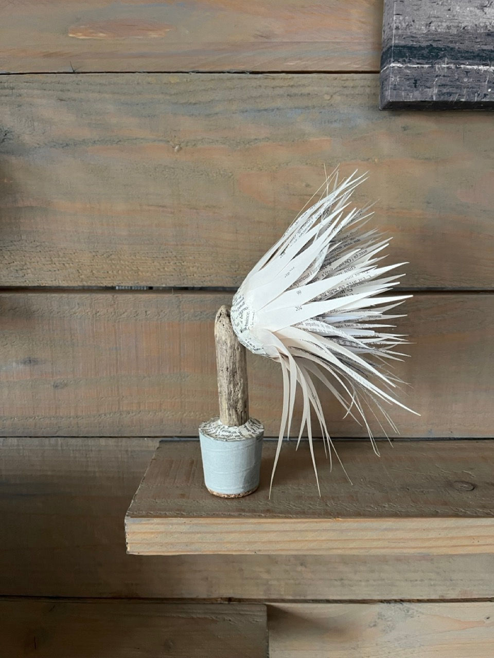 Katy se distingue par son équilibre entre douceur et caractère.
Avec ses 20 cm de hauteur, elle s’élève sur un socle en béton aux lignes nettes, moulé dans un pot de yaourt. Son dessus, recouvert de petits fragments de papier imprimé, dévoile subtilement les mots qu'il porte.
Son bois large de 12 cm ancre la pièce, tandis que sa fleur, juste assez épanouie, laisse entrevoir un cœur en papier chiffonné rose, tendre et délicat.