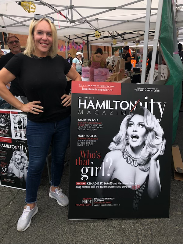 Woman beside Hamilton City Magazine featuring drag entertainer