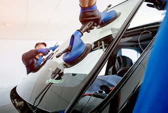 Automobile special workers replacing windscreen or windshield of a car in auto service sta