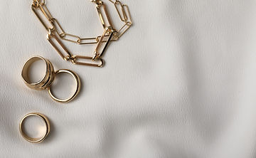 Stylish golden bijouterie on white fabric, flat lay