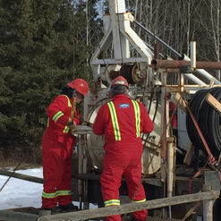 Two workers working on a water well testing system
