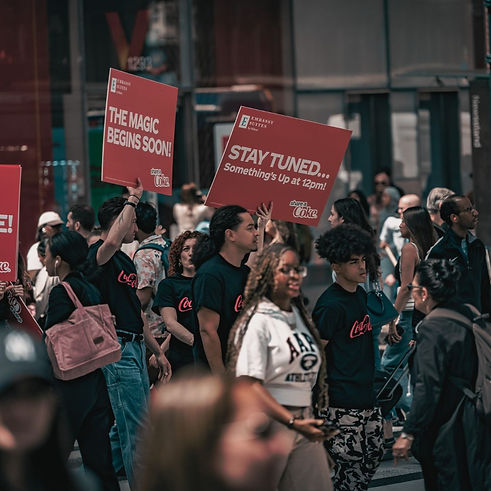 Brand ambassadors setting the stage in herald square park with signs readin "the magic begins soon"