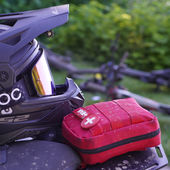 A black motorcycle helmet and a red IFAK kit