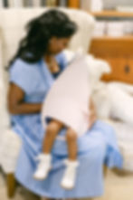 Mother breastfeeding baby with arm-worn Snugghug Nursing Cover