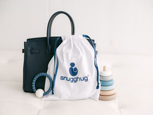 Snugghug Nursing Cover and several small toys near a diaper bag.