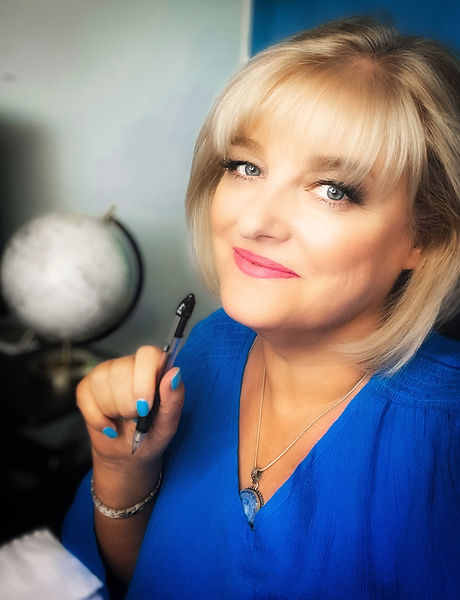 a photo of Shelley Watson, short blonde hair, blue shirt, holding pen, with globe in background