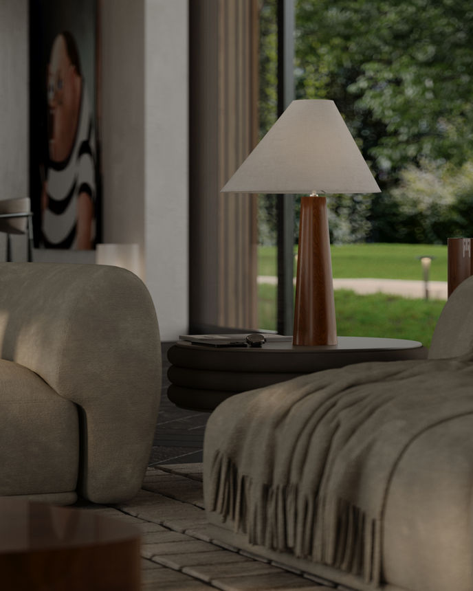 A close-up of a warm, contemporary living room corner featuring a rounded beige armchair, a soft wool throw, and a sculptural side table with a wooden-based table lamp. A modern portrait painting and large window revealing lush greenery add depth and atmosphere.