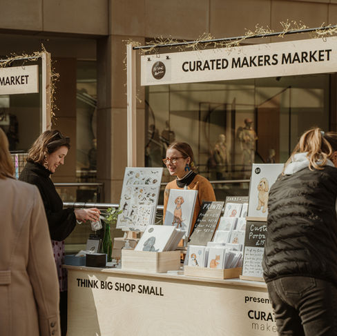 A pet portrait artist stood behind a Curated Makers Market stall.