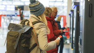 Female passenger buying train ticket at self service ticket machine at the station.