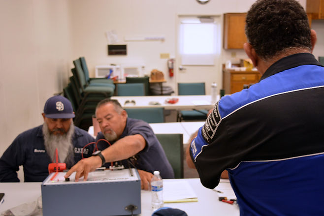 Image of fleet technicians training on an electrical circuit board with an instructor in the foreground.