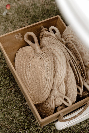 Woven fans in a wooden box, styled for an outdoor wedding by The Wedding Stylist