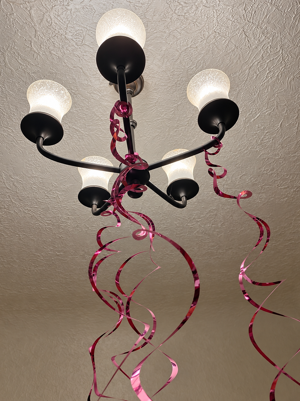 Pink birthday ribbons curling from the chandelier