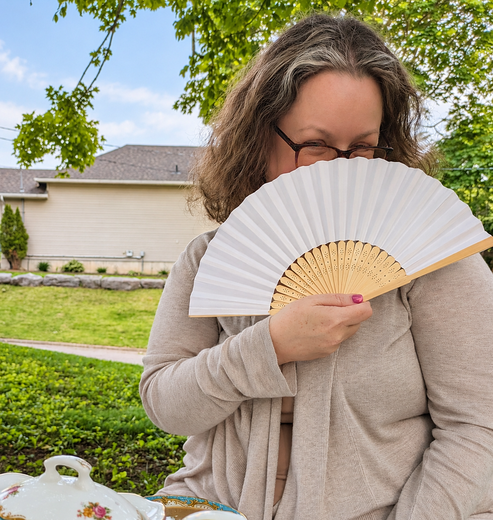 A friend smiling playfully behind a white fan during an outdoor gathering