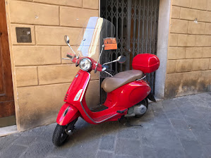 Red Vespa parked in an alleyway in Siena