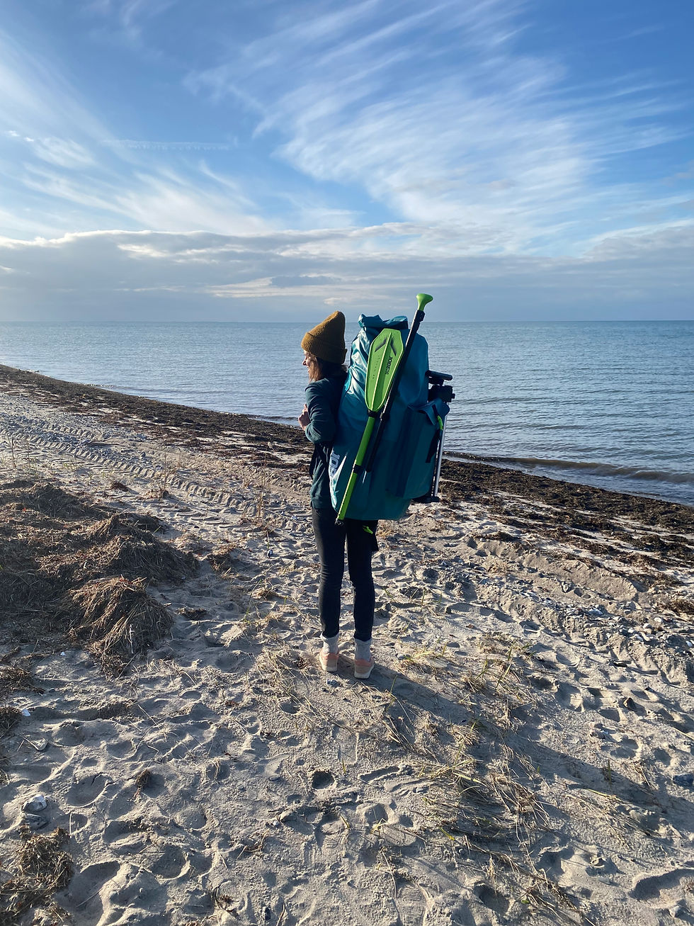 En kvinde står på stranden med sin SUP.