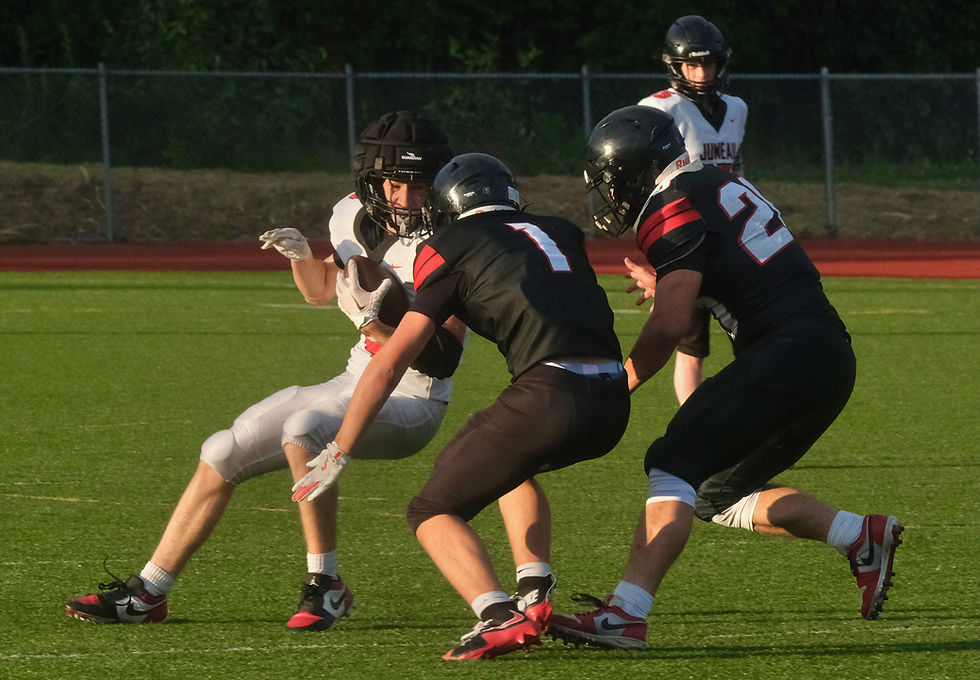 Juneau-Douglas High School: Yadaa.at Kalé sophomore Carter Day (1) and senior Jaxin Jim (20) tackle sophomore Jude Rushton during the Crimson Bears scrimmage at Thunder Mountain Middle School's Falcons' Field on Monday, August 10, 2026. (Klas Stolpe / Juneau Independent)