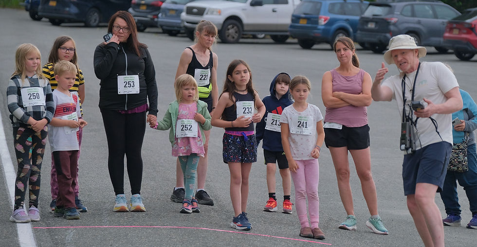 One-mile racers in the Midsummer Night Run listen to race starter Brian McTague at the start line on False Outer Point, Tuesday, Aug. 11, 2026. (Klas Stolpe / Juneau Independent)