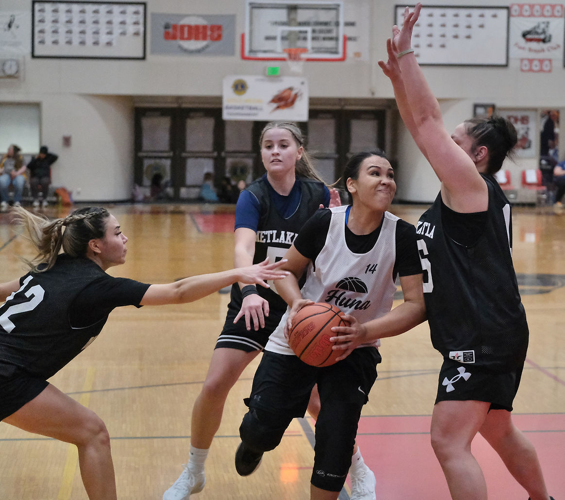 Hoonah's Janelle Staveland (14) drives under pressure from Metlakatla's Alexis Russell (12), Ryley Booth (5) and Sally King during their Womens bracket elimination game on Wednesday, March 25, at the Juneau Lions Club 77th Gold Medal Basketball Tournament in the Juneau-Douglas High School: Yadaa.at Kalé George Houston Gymnasium. Metlakatla won 66-32. (Klas Stolpe / Juneau Independent)