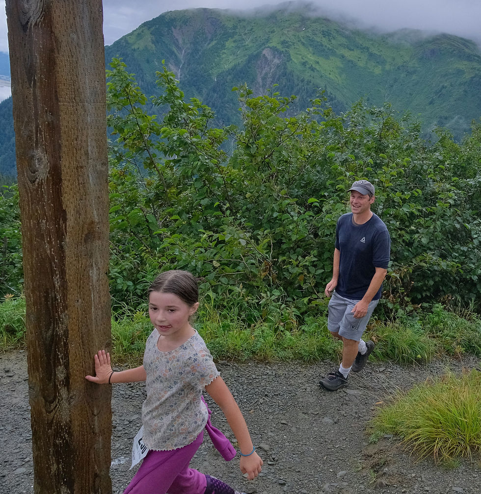 Isla Taintor, 8, touches the Father Brown Cross at the finish of the Goldbelt Tram-Mount Roberts Trail Run as father Matt Taintor, 46, watches, on Saturday, Aug. 22, 2026. Isla was the top runner under age 18. (Klas Stolpe / Juneau Independent)