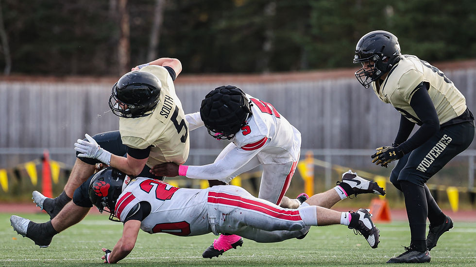 Juneau-Douglas High School: Yadaa.at Kalé senior Jaxin Jim (20) and junior Sylvion Washington (5) tackle South Anchorage senior Ethan Yarrington (5) during the Crimson Bears' 42-12 loss to the Wolverines in the ASAA First National Bowl semifinal football game at South High School, Saturday, Oct. 17, 2026. South advances to play West Anchorage next weekend for the state championship. (Photo courtesy Stephanie Burgoon)