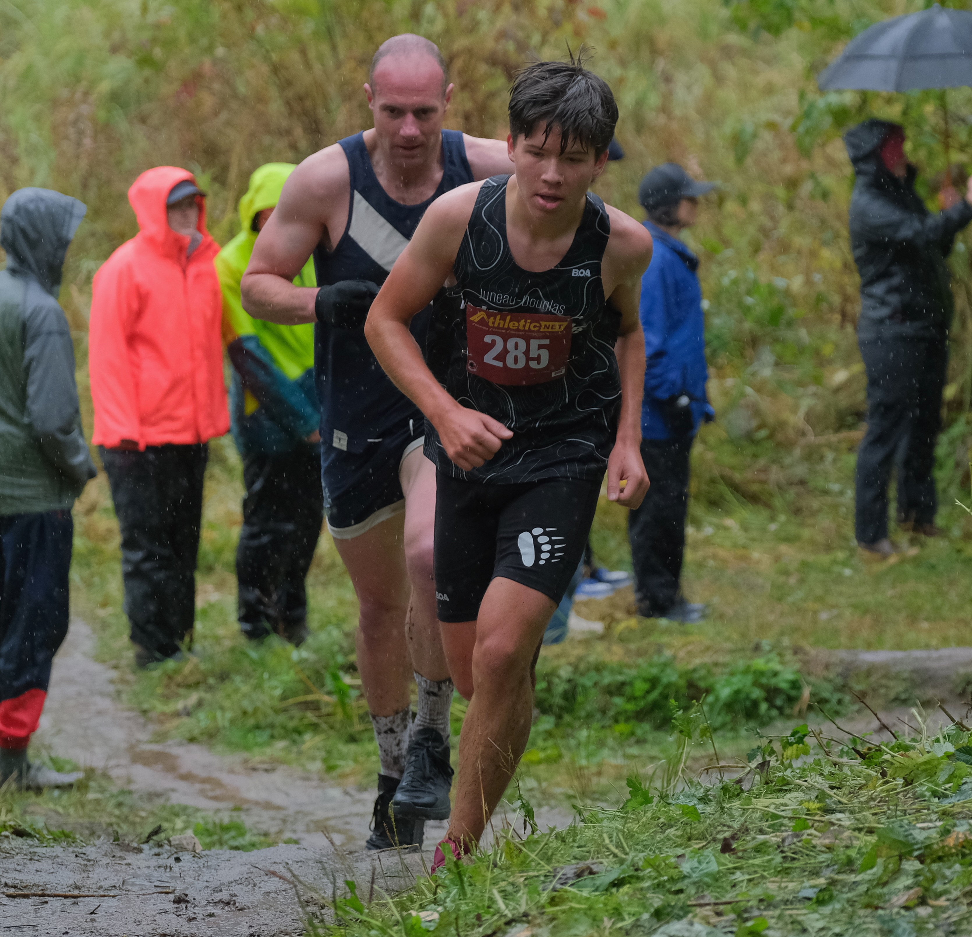 Juneau-Douglas High School: Yadaa.at Kalé senior Dan Degener (285) powers up a hill in front of Juneau local Brandon Ivanowicz in the JV/Open Community 5K race during the Region V Cross Country Running Championships on Saturday, Sept. 26, 2026. (Klas Stolpe / Juneau Independent)