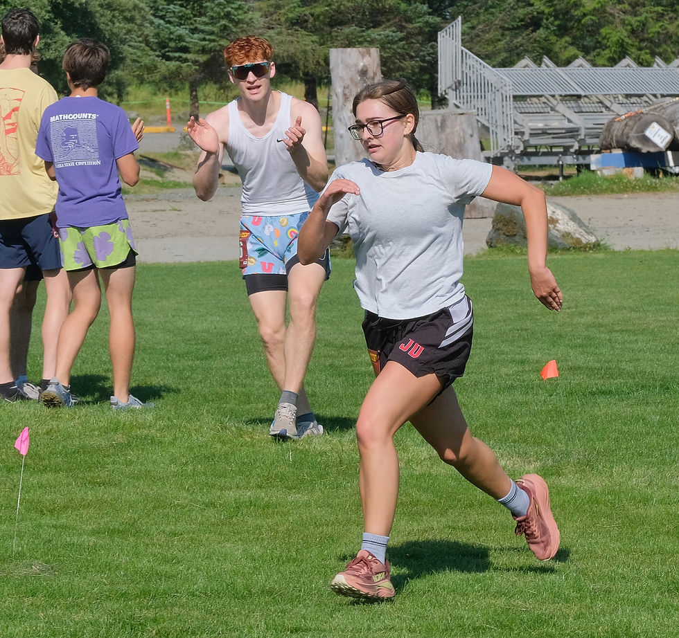 Juneau-Douglas High School: Yadaa.at Kalé sophomore Kira English is cheered on by senior co-captain Erik Thompson as she approaches the finish of the Juneau Sayéik Invitational 5K Girls Vs. Women race along Treadwell Mine Trail at Savikko Park on Saturday, Aug. 15, 2026. (Klas Stolpe / Juneau Independent)