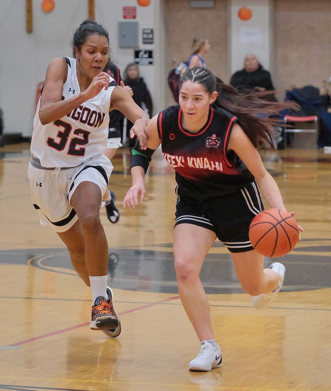 Angoon's Tasha Heumann (32) defends Kake's Katie Jackson during Angoon's 56-48 Womens bracket elimination game on Wednesday, March 25, at the Juneau Lions Club 77th Gold Medal Basketball Tournament in the Juneau-Douglas High School: Yadaa.at Kalé George Houston Gymnasium. (Klas Stolpe / Juneau Independent)