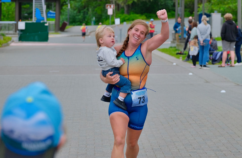 Kylie Larson from Galesburg, Illinois, carries her 18-month-old son Stone across the finish line of the Aukeman Triathlon at the UAS plaza after finishing the sprint course, Sunday, August 2, 2026. (Klas Stolpe / Juneau Independent)
