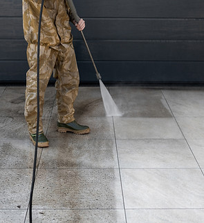 Worker cleaning tiles in backyard with high pressure water jet equipment. Visible before a