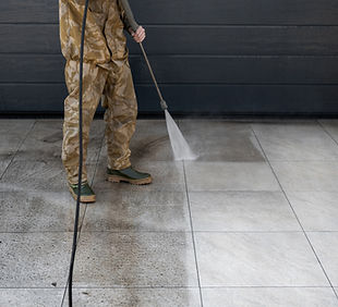 Worker cleaning tiles in backyard with high pressure water jet equipment. Visible before a