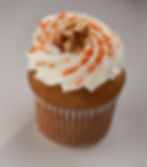 Cinnamon graham cracker bottom below our moist walnut carrot cake topped with homemade cream cheese frosting with sprinkles and a walnut.