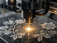 Close-up of a laser engraving tool cutting a detailed floral design into black granite, with sparks flying, representing the Craft step of memorial creation