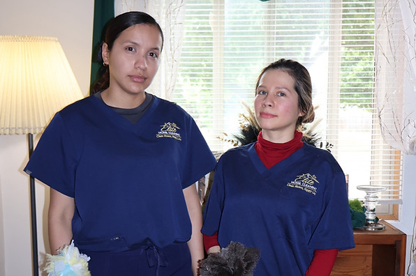 Two Elite Home Cleaning team members holding cleaning tools