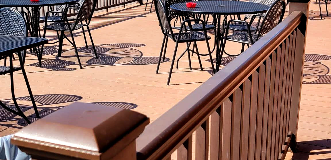 Outdoor restaurant patio with tables and chairs on a wooden deck in Longville.