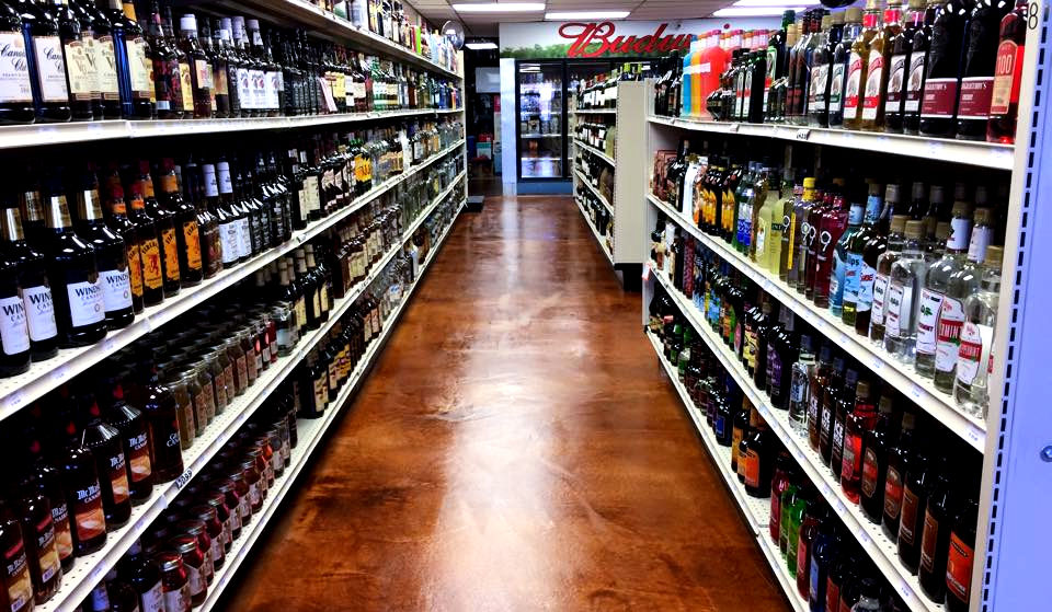 Liquor store aisle with many different bottles of alcohol, Budweiser sign present.