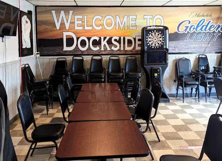 Interior of Dockside Bar Welcome To Docksider with tables and chairs, darts.